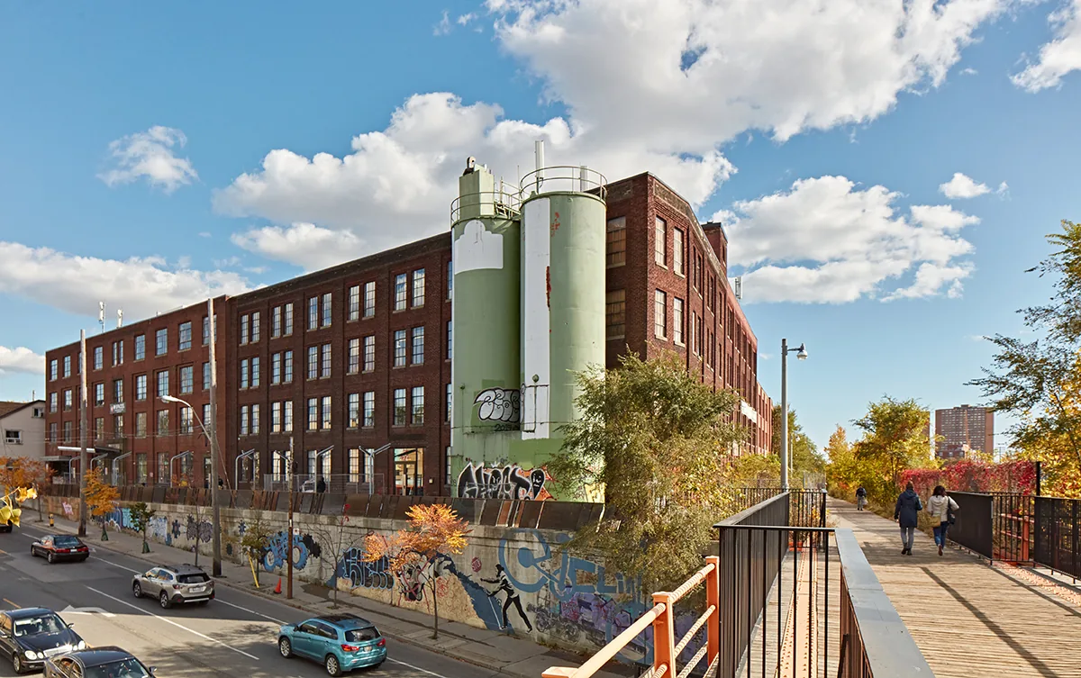 The Planet at 1655 Dupont Street — a brick-and-beam building with green silos, seen from the West Toronto Railpath